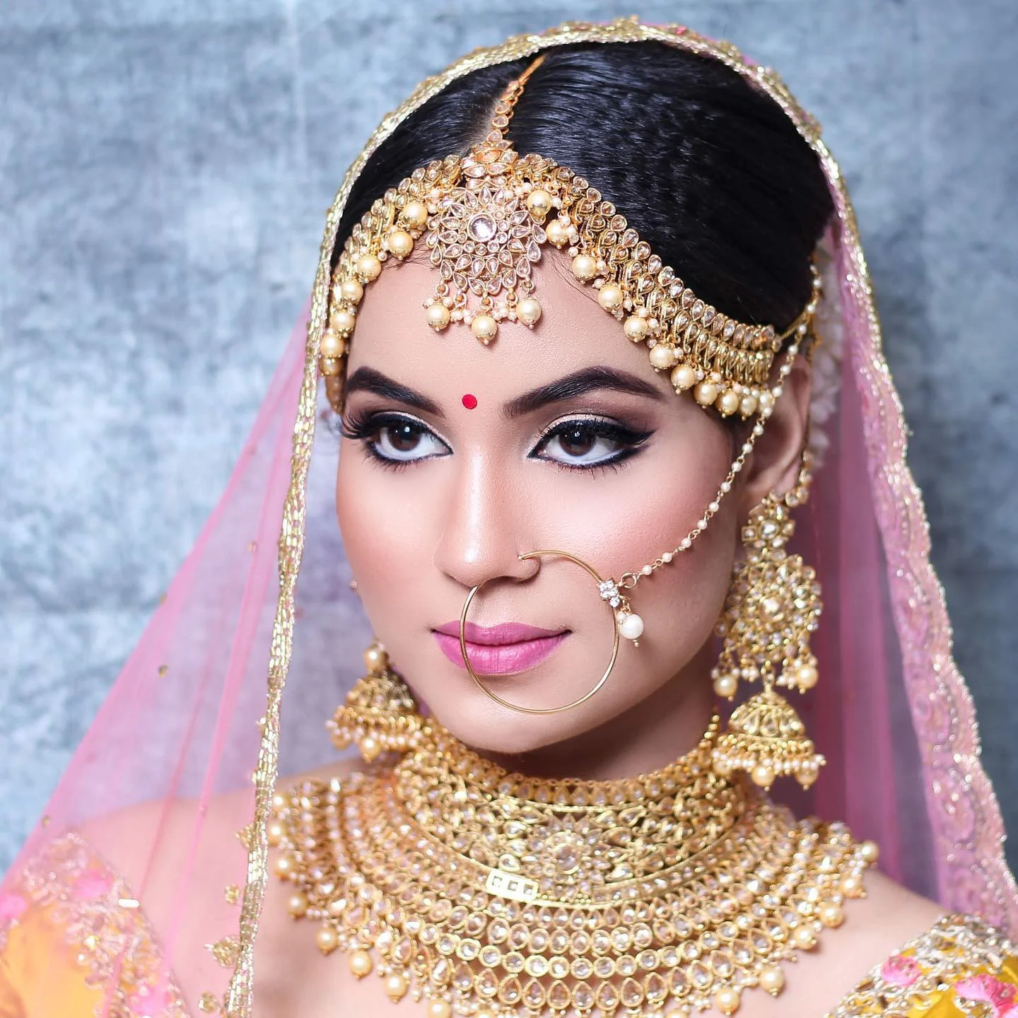 Bride in blue and gold with a pearl maang tikka