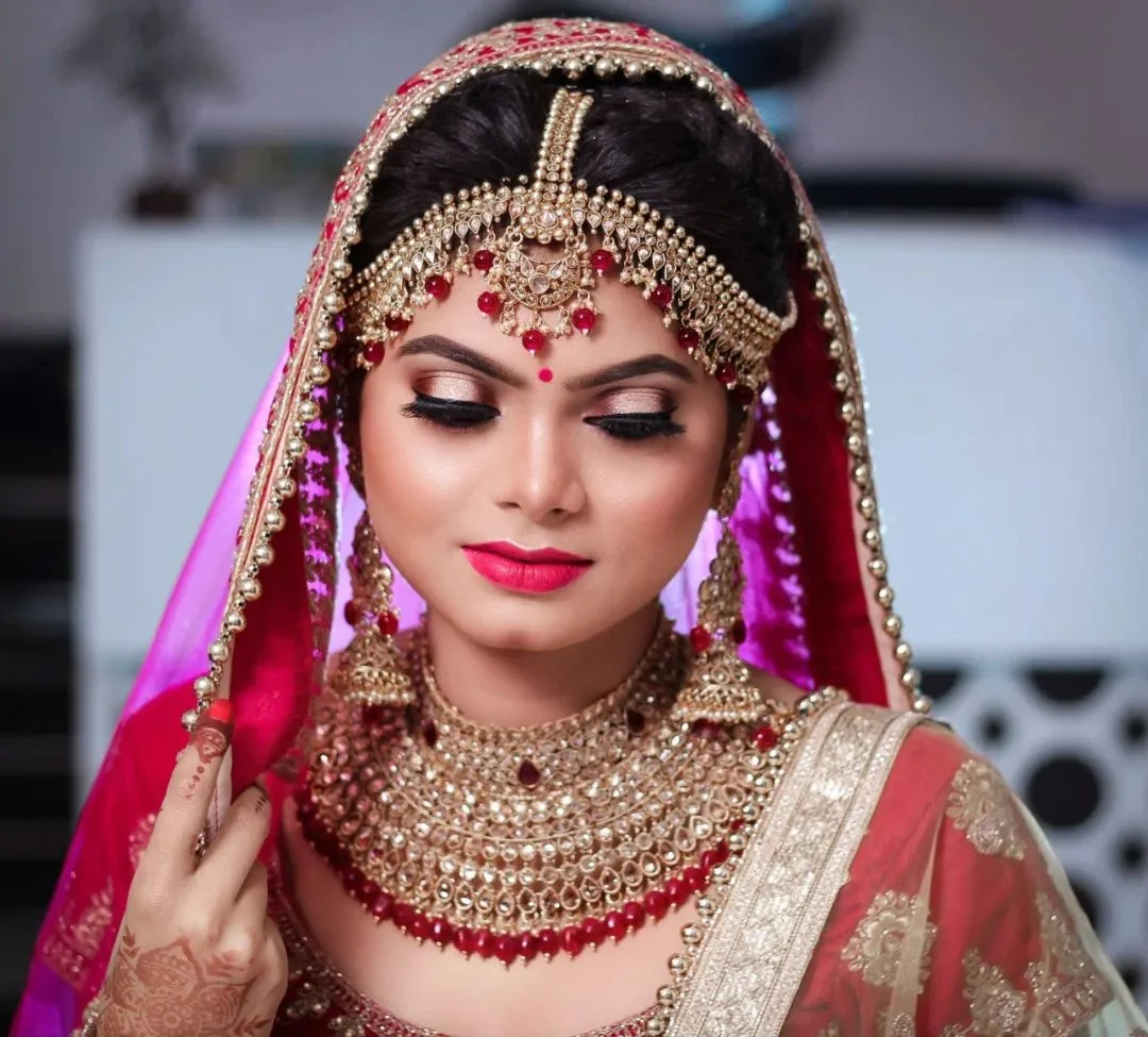 Bride in a magenta dupatta with gold bridal jewellery