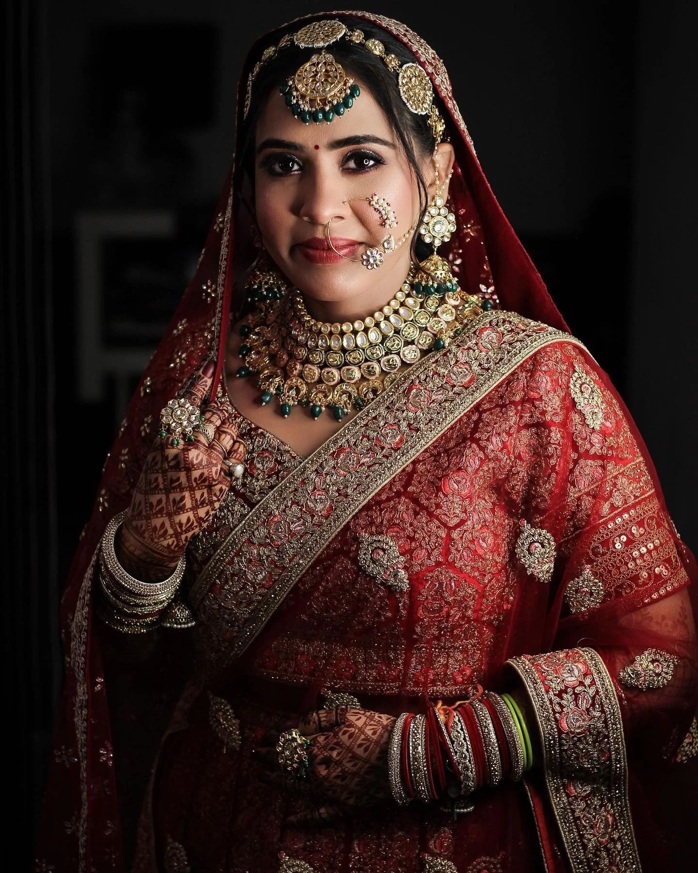 Bride in a maroon Banarasi lehenga with a gold border and layered necklaces