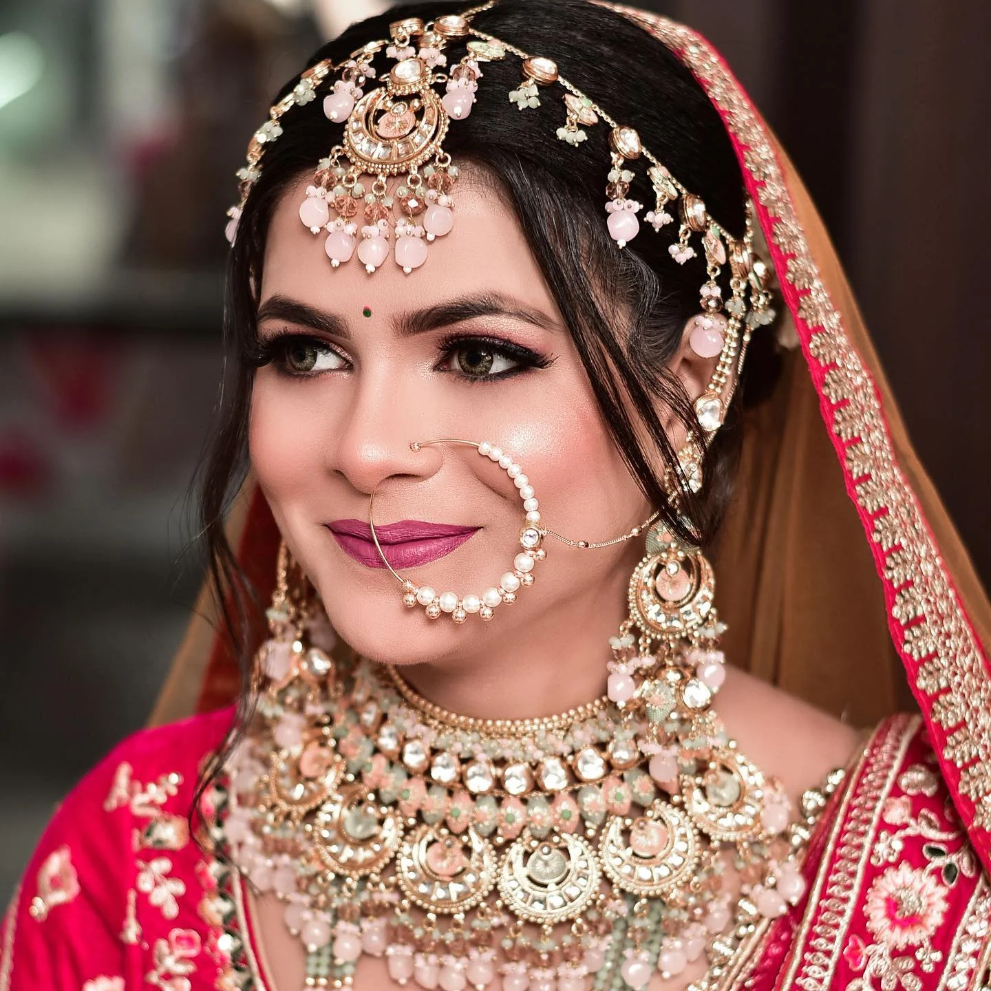 Bride in pink and gold wearing a traditional nath